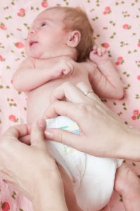 Mother changing a bab girl's diapers